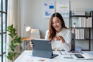 Wall Mural - asian businesswoman smiling while working with tablet and documents at the office