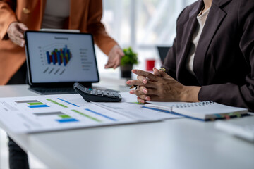 Businesswoman listening to colleague explaining financial charts on tablet