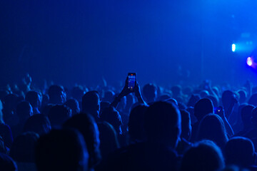 Hands holding phone and making photos on the concert.