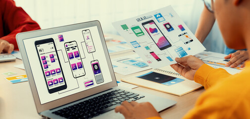 Panorama banner of startup UX developer or company employee design user interface or UI prototype for mobile application or website software with software display on laptop monitor in office. Synergic