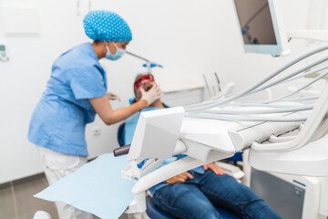 Male patient receiving teeth whitening treatment from a dental nurse at the clinic.