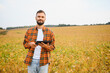 © Serhii - Agronomist inspecting soya bean crops growing in the farm field. Agriculture production concept.
