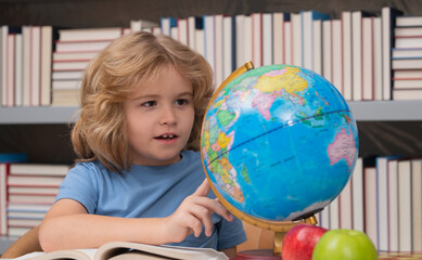 Fototapete - School child looking at globe in library at the elementary school. Little student school child. Portrait of nerd student with school supplies. World globe.