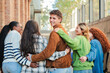 © Jose Calsina - A group of students walk on the university campus, while one of them turns back and looks at the camera smiling. Multiracial teenage friends at the high school going to the class to study together