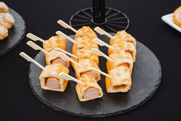 A truly delicious tray of hot dogs that are expertly wrapped in flaky pastry, elegantly served on skewers, making them perfect for any gathering, party, or special event celebration