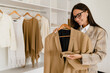 © mary_markevich - woman wearing elegant beige jacket standing in fashion showroom on shopping, modern design, choosing