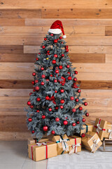 Canvas Print - Christmas tree with red baubles, gift boxes and Santa hat near wooden wall