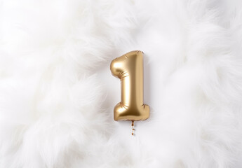 Golden number one balloon celebrating first birthday on white fur