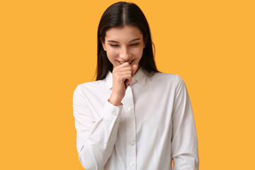 Beautiful happy young businesswoman laughing on yellow background