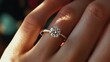 © somneuk - A close-up of a sparkling diamond engagement ring worn on a finger, highlighting elegance and beauty in a soft, warm light.
