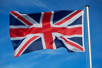 Wall Mural - The flag of  Great Britain, United Kingdom, UK, flutters in the wind against a blue cloudless sky