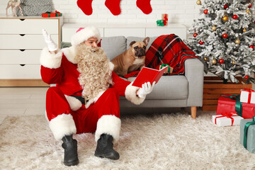 Canvas Print - Surprised Santa Claus reading book with cute French bulldog at home on Christmas eve