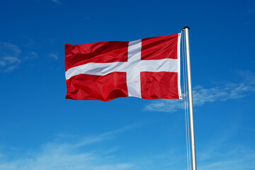 Wall Mural - The flag of Denmark flutters in the wind against a blue cloudless sky