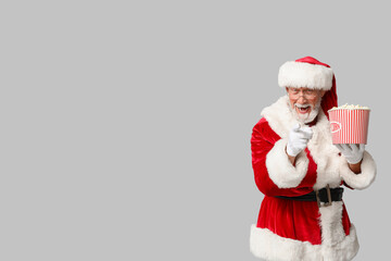 Wall Mural - Santa Claus with bucket of tasty popcorn on grey background