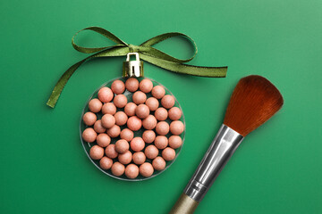 Poster - Christmas ball made of cosmetic product, bow and makeup brush on green background, flat lay