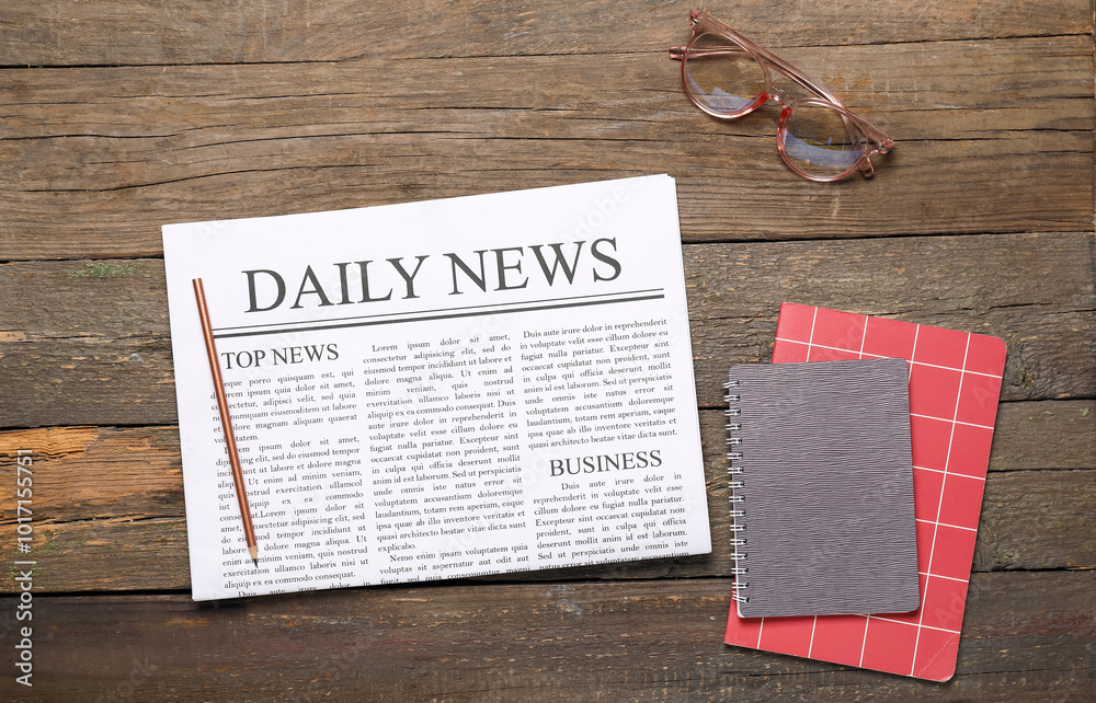 Newspaper with notebooks and glasses on wooden background. Top view