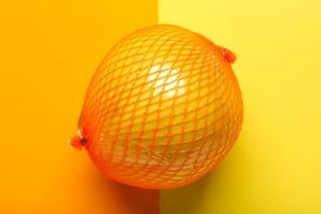 Fresh pomelo fruit in net on colorful background