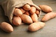 © New Africa - Sack with fresh raw sweet potatoes on wooden table, closeup