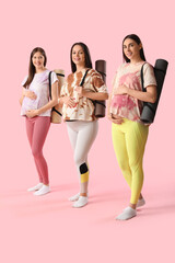 Canvas Print - Beautiful young sporty pregnant women with yoga mats on pink background