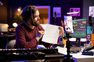 Poster - Young artist pointing at music sheet notes to explain on piano keys, teaching people how to play electronic keyboard in home studio. Musician singer playing midi controller keys, master class.