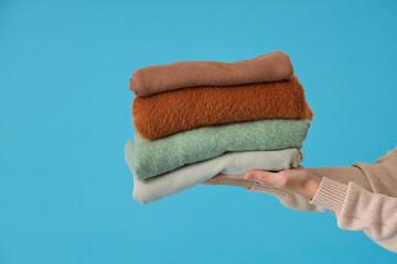 Wall Mural - Female hands with stack of stylish clothes on blue background, closeup