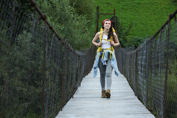 Poster - Young hiker walking on wooden bridge over river