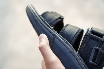 A close-up shot of a black sandal, showcasing the texture of the leather and fabric, as well as the buckles and straps.