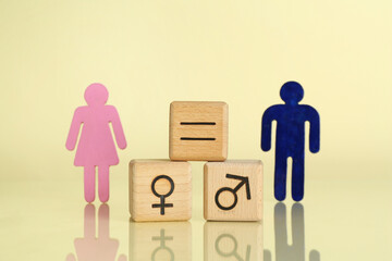 Wall Mural - Gender equality concept. Wooden cubes with male and female figures on light yellow background