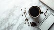 © Naveed - An elegant flat lay of a black coffee cup placed on a marble countertop, with scattered coffee beans and a small notebook beside it.