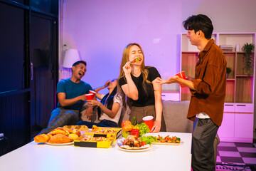 Four Asian friends, two men and two women, celebrate in an office party. They enjoy a fun-filled night with food, drinks, and laughter, bonding over teamwork and friendship.