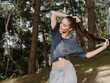 © SHOTPRIME STUDIO - Relaxed woman stretching her hair outdoors, wearing casual sportswear, enjoying nature in a serene environment surrounded by trees Wellness and fitness concept