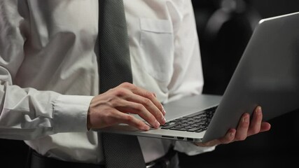 Wall Mural - A businessman works with a laptop in close-up in a dark office