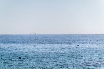 Wall Mural - Calm blue sea with the silhouette of a large ship on the horizon