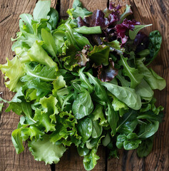 A selection of tasty salad greens lying on a rustic pale oak dining table. top view.