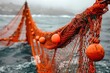 © Elena - Close up of fishing nets with bright orange floats on a boat amidst the sea waves