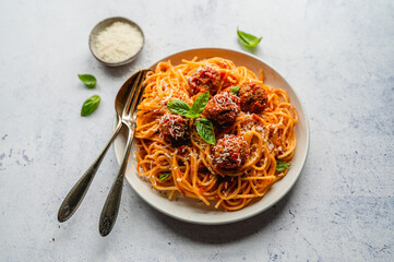 Close up of plate of spaghetti and meatballs on light background.