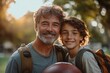 © Rahul - happy father hugging teenage son holding football while walking in green park, Generative AI
