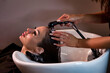© Alex Vog - Hairdresser hands washing lady head in spa salon for create hairstyle. Hairstylist wash woman hair with shampoo in barber shop. Concept of customer service at hair salon, haircare. Copy ad text space