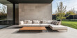 © JuanM - Modern outdoor lounge area with sleek sofa and wooden coffee table beside lush garden