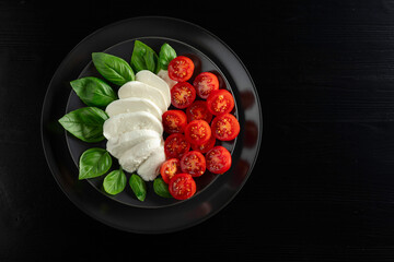 Wall Mural - Mozzarella with basil and cherry tomatoes on an old wooden table.