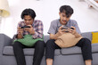 © Gatot - Two Young Asian Men Wearing Casual Clothes Together Playing Video Games Online On Mobile Phone At Home