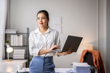 Wall Mural - Businesswoman working on laptop and thinking about project in modern office