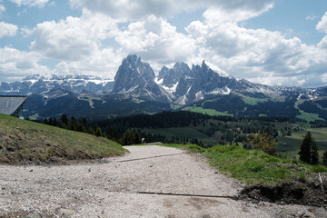 Natural pathway among landscape of Alpe de Suisse, The Seiser Alm with green meadows, lovely hill range with typical rocky mountains ridge of the dolomites plateau- South Tyrol, Italy