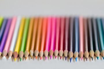 Man is coloring white with colored pencils. palette learning closeup concept. a w is lying on a white with colored pencils. a white and notebook with colored pencils lies on a white lifestyle.