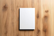 © Natalia - Top view of a blank white book or notebook on a wooden surface with natural grain texture.