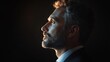 © Joachim - Profile portrait of a contemplative man with a beard, dressed in a suit, highlighted dramatically by side lighting against a dark studio backdrop.