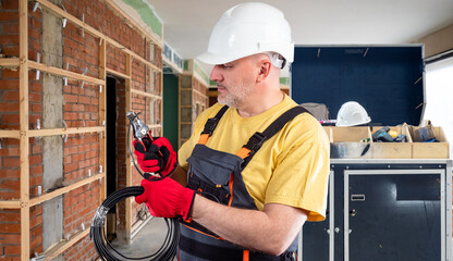 Poster - man electrician with wire. electrification works. electrical installation work inside building. elec