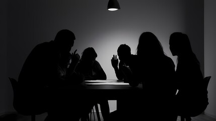 Wall Mural - Silhouettes of a diverse group discussing ideas at a dimly lit meeting.