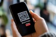 © Nico - Digital Coupons and QR Codes: A smartphone showing a QR code for a 'Black Friday Sale' discount, ready to be scanned at checkout.