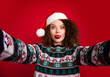 © deagreez - Photo of pretty young woman make selfie show tongue out wear christmas festive sweater isolated on red color background